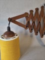 Vintage wooden scissor wall lamp with downward-facing shade.