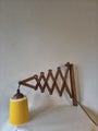 Vintage wooden scissor wall lamp with downward-facing shade.