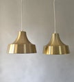 Two gold vintage pendant lamps with conical shape and polished metal surface