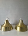 Two gold vintage pendant lamps with conical shape and polished metal surface