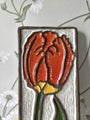 Vintage ceramic wall tile with red flower relief on white background
