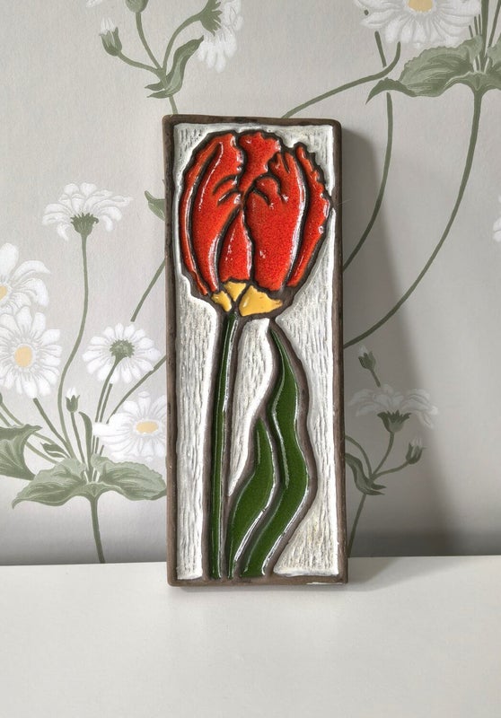 Vintage ceramic wall tile with red flower relief on white background