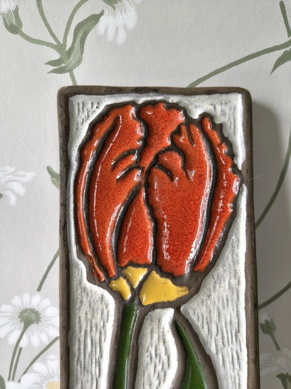 Vintage ceramic wall tile with red flower relief on white background